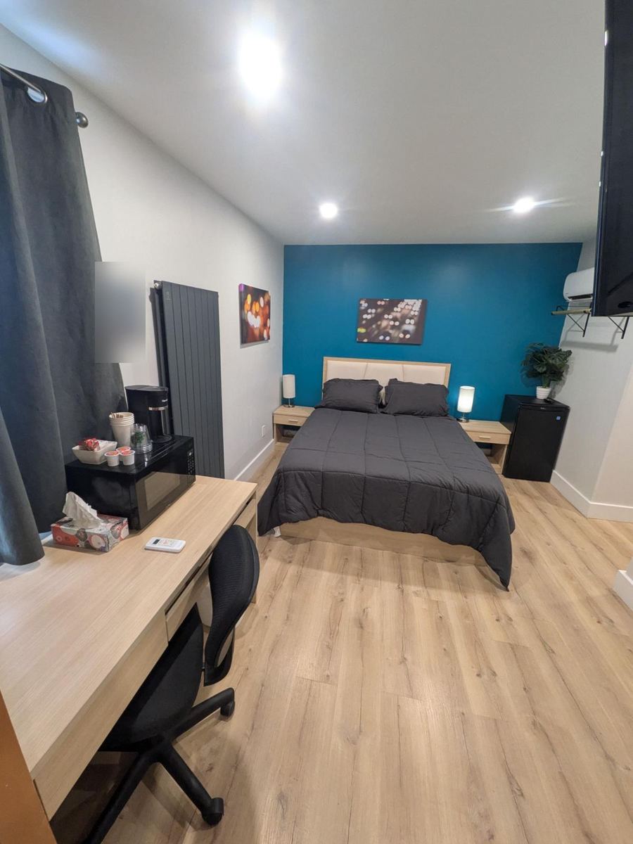 Queen bed with teal accent wall, desk, microwave and coffee station